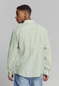 Groen en witte gestreepte langemouwen shirt gemaakt van lichtgewicht stof, met een klassieke kraag en knoopmanchetten.