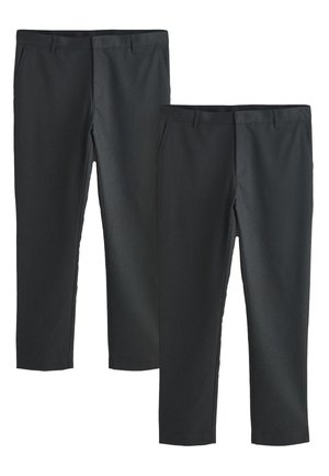 Mężczyzna w ciemnoszarych eleganckich spodniach i białej koszuli z szarymi pionowymi paskami, ręka w kieszeni, pokazany od talii w dół.