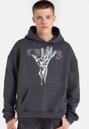 Szara bluza z kapturem z przednią kieszenią, ozdobiona białym nadrukiem przedstawiającym cieknącą dłoń oraz dużym napisem nad nią. Miękki materiał o luźnym kroju.