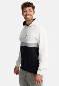 Hætte sweatshirt i en farveblok-design med hvide, grå og marineblå paneler. Blødt stof med snøre og broderet logo detalje.