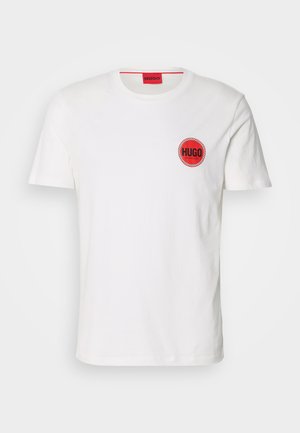 T-shirt en coton blanc avec un logo rond rouge entouré d'une bordure à damiers. Design à manches courtes et col rond.