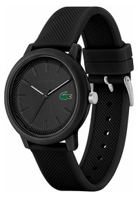 Montre en silicone noire avec un cadran texturé, des marqueurs d'heure minimalistes et un logo de crocodile vert brodé. Présente une couronne et une boucle en argent.