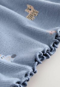 Heller blauer Stoff mit einer strukturierten Oberfläche, der mit Rüschensäumen und kleinen Tierillustrationen in Farben wie Schwarz, Pink und Pfirsich versehen ist.