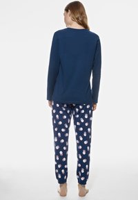 Haut à manches longues marine avec un col rond, associé à un pantalon à pois marine et rose, doté de poignets élastiques aux chevilles.