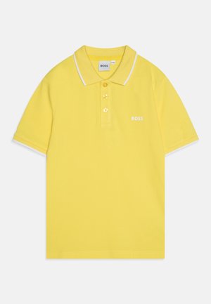 Polo shirt jaune en coton, avec un col classique, une patte de boutonnage à trois boutons et des bordures blanches le long du col et des manches.