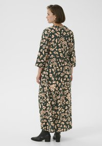 Maxikleid mit grünem Hintergrund und beigen Blumenmustern, langen Ärmeln, rundem Halsausschnitt, elastischem Bund und fließender Silhouette.