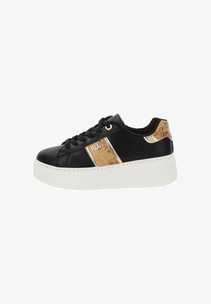 Sneaker en cuir noir avec une semelle plate-forme blanche, présentant un panneau décoratif de couleur claire avec un design de carte et des accents dorés.
