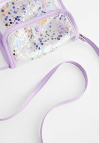 Transparent handväska med lila detaljer, prydd med stjärnformade paljetter, en tryckknappsförslutning och en matchande axelrem. Slät yta och genomskinlig design.