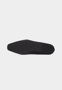 Semelle de chaussure noire avec un bout carré et un talon bas, présentée à plat sur un fond blanc.