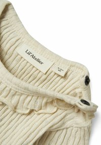Beige ribbet strikket topp med en volangkrage, med knappelukking og et merke som sier "Lil' Atelier." Teksturen er myk med små hull.
