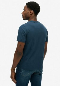 Navyblå kortærmet t-shirt lavet af blød bomuld, med rund hals og en tætsiddende pasform, parret med blå jeans.