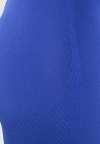 Primer plano de una tela azul texturizada y elástica que muestra un patrón sutil, con una superficie suave y un ligero brillo.