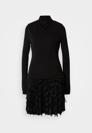 Sort kjole med høj hals, lange ærmer og en tekstureret plisseret nederdel med stofdetaljer. Glat top med samlet detaljer.