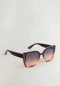 Lunettes de soleil dégradées marron avec une grande monture carrée, présentant un accent métallique doré sur le bord extérieur et des branches marron foncé.