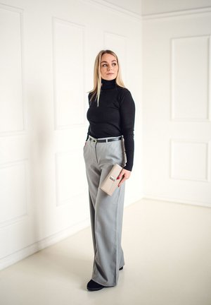 Black turtleneck, high-waisted gray wide-leg trousers, black belt, beige clutch, and black footwear against a neutral background.