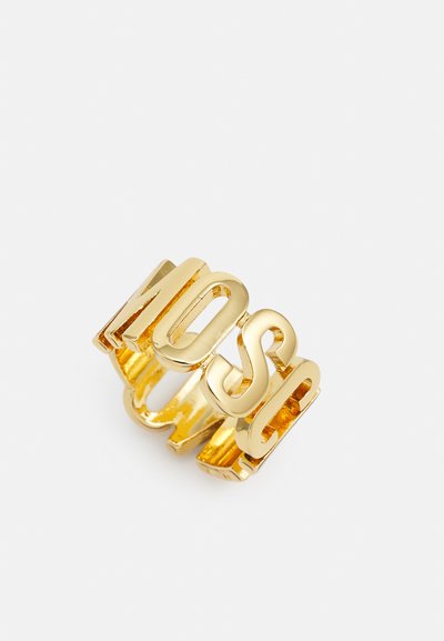 Gouden ring met opvallende, uitgesneden letters die "NOSE" spellen. Het ontwerp is chunky, met een gladde, reflecterende oppervlakte en een open bandstijl.