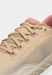Εγγύς εικόνα μιας μπεζ και ροζ αθλητικής παπουτσιού με ανθεκτικό πλέγμα στο πάνω μέρος, επίπεδα μπεζ κορδόνια, επενδυμένη γλώσσα και υφή σόλας από καουτσούκ.