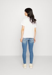 White cotton t-shirt, relaxed fit, paired with light blue skinny jeans featuring faded accents, completed with white sneakers.