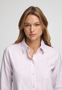 Långärmad knapp-up skjorta i ljusrosa med vita ränder, med klassisk krage och en liten broderad logotyp på vänster bröst.