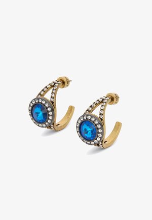 Boucles d'oreilles en tone or avec une pierre précieuse bleue centrale entourée de rhinestones transparents, présentant un design courbé et des accents délicats.