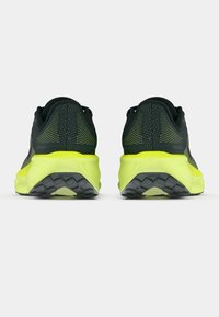 Ζεύγος μαύρων και νέον κίτρινων παπουτσιών τρεξίματος απεικονισμένο από πίσω, τονίζοντας την υφή της φτέρνας και το σχέδιο της σόλας.