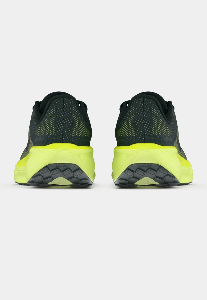 Un par de zapatillas de correr negras y amarillas neón vistas desde atrás, destacando el talón texturizado y el patrón de la suela.