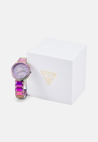 Guess-Uhr mit lila Zifferblatt und Kristallakzenten, ausgestattet mit einem mehrfarbigen Gliederarmband. Lieferung erfolgt in einer weißen markierten Schachtel.