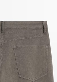 Graue Jeans aus Denim mit geradem Schnitt, ausgestattet mit einer Gesäßtasche und dezenten Nahtdetails. Der Stoff hat eine glatte Textur.