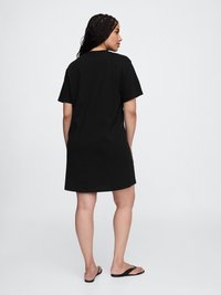 Robe T-shirt en coton noir avec des manches courtes, coupe décontractée, ourlet droit et détail de couture au dos, associ�ée à des tongs noires.