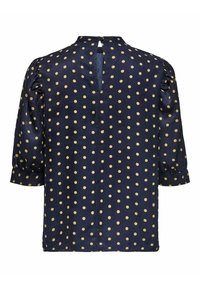 Blouse bleu marine à pois beige, manches trois-quarts bouffantes, ouverture dos en forme de clé et petit col.