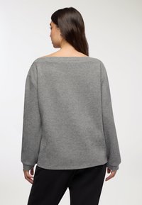 Felpa grigia, over size, con una texture morbida, collo largo e maniche lunghe. Presenta una vestibilità comoda, adatta per un abbigliamento casual.