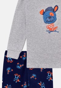 Gray long-sleeve shirt with a blue bear graphic and "GOOD NIGHT" text. Navy pants with colorful bear and skateboard patterns. Soft cotton material.