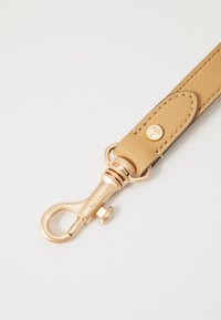 Tan leren riem met een gladde textuur, voorzien van een gouden metalen clipslot en -hardware, decoratieve stiksels en een logo-detail.