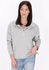 Lys grå pullover, kvart-lynlås design, lavet af blødt stof, har lange ærmer og en løs pasform. Stylet med casual blå jeans.