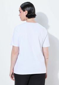 T-shirt bianco a maniche corte in cotone, con girocollo e texture liscia, vista da dietro con un design minimalista.