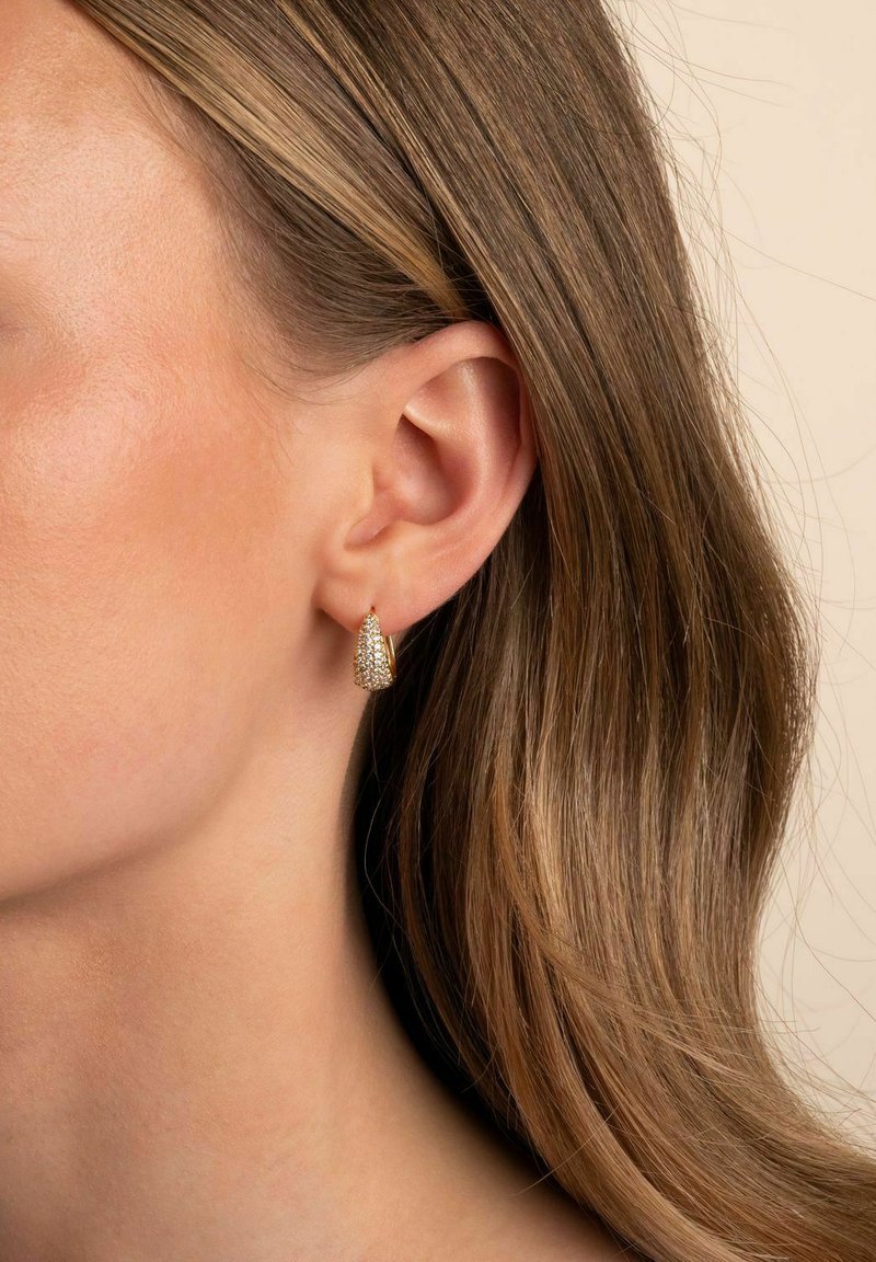 Guldtonade hängande örhängen med en strukturerad, avsmalnande design som liknar en kon. Lätta, med en liten krok för enkel användning.