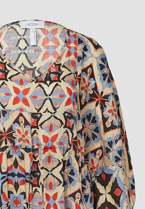 Patterned blouse with V-neckline, featuring a mix of red, blue, and black floral designs on a beige background, made of lightweight fabric.