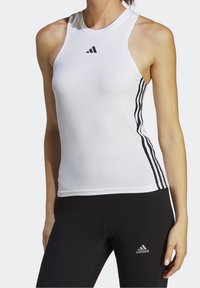 Canotta atletica bianca con design aderente, caratterizzata da un collo rotondo e dettagli con tre strisce nere ai lati. Logo Adidas sul petto.