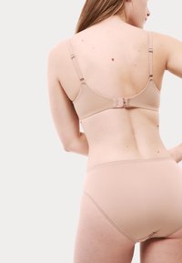 Ensemble de soutien-gorge et culotte nude en tissu lisse. Le soutien-gorge dispose de bretelles réglables et d'une fermeture à crochets, tandis que la culotte présente un design sans couture.