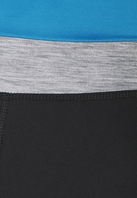 Legginsy kompresyjne z czarnym dołem, szarym pasem i niebieską górną częścią, wykonane z gładkiego, elastycznego materiału z kontrastującymi fakturami.