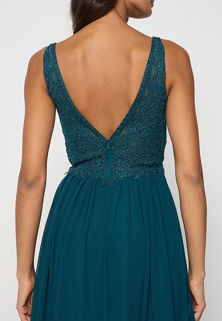 Vestido azul verdoso con un diseño de espalda en V, corpiño adornado con intrincados bordados de cuentas y falda fluida hecha de tela ligera.