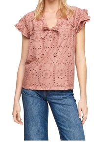 Maglia rosa ricamata con scollatura a V, maniche corte a volant e motivi floreali intagliati. Abbinata a jeans in denim per un look informale.
