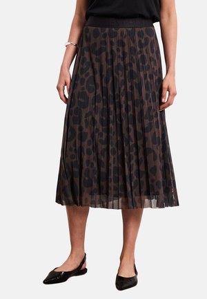 Kvinde iført en brun plisseret midi nederdel med sort leopardprint, sort top, sølv armbånd og sorte spidse slingback-flats.