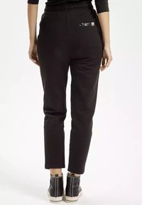 Czarne dresy z dopasowanym krojem, elastycznym pasem i małą kieszenią z tyłu. Gładki materiał o minimalistycznym designie.