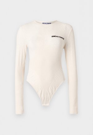 Body en crème à manches longues avec motifs texturés subtils, col rond, et logo "SINÉAD O'DWYER" imprimé sur la poitrine et l'étiquette du col.