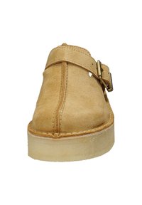 Scarpa slip-on in suede beige con una larga fascia e un dettaglio in ottone. Suola spessa in gomma testurizzata con bordi cuciti per una maggiore durata.