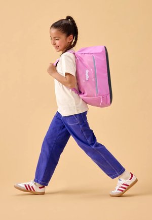 Rosa Rucksack mit grauen Akzenten, ausgestattet mit einer vorderen Reißverschlusstasche und Sternmustern. Getragen von einem Kind in einem weißen T-Shirt und blauen Hosen.