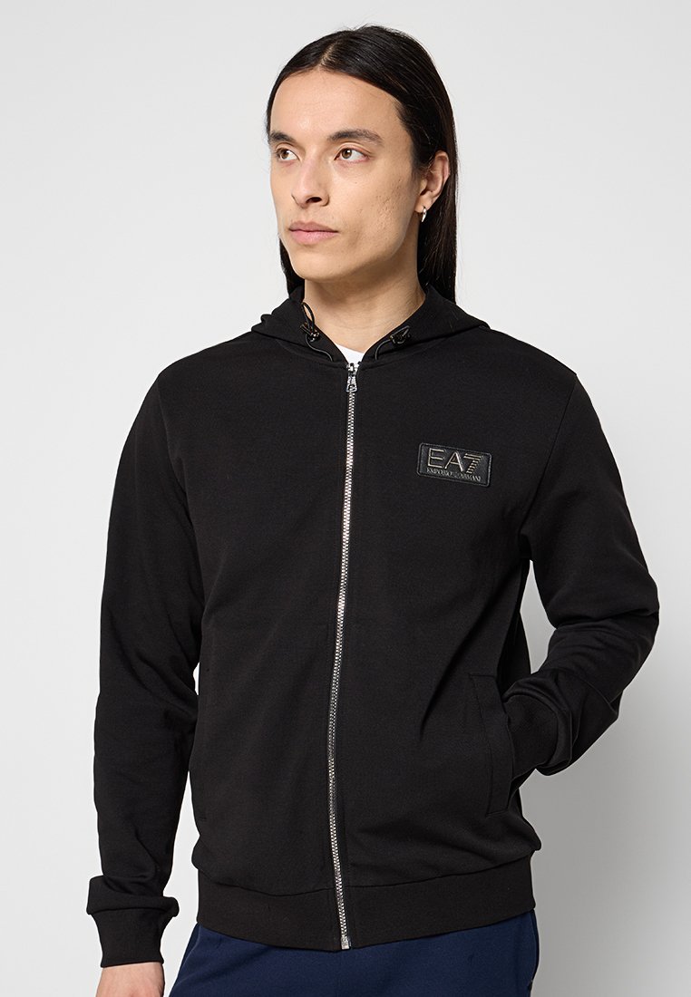 Schwarze Zip-Hoodie aus Baumwollstoff, mit einer Fronttasche, Kordeln und einem "EA7"-Logopatch auf der Brust.