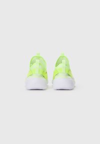 Baskets slip-on vert fluo et blanches vues de l'arrière, avec des languettes de traction et un dessus en maille extensible.