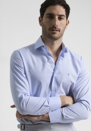 Camisa de vestir a rayas en azul claro con cuello abotonado, que presenta sutiles patrones de cuadrícula en blanco y morado y mangas largas.